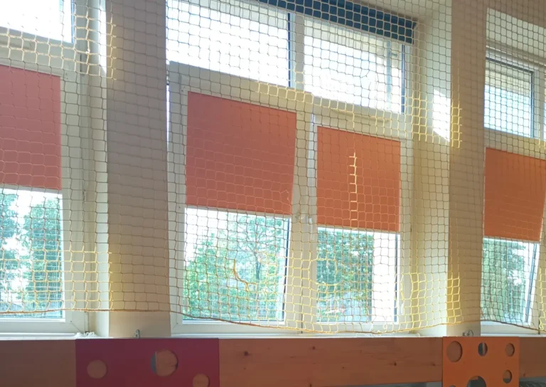 Niebieskie rolety materiałowe z prowadnicą na sali gimnastycznej- Agmart producent rolet