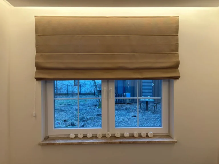 Beżowa roleta rzymska w oknie